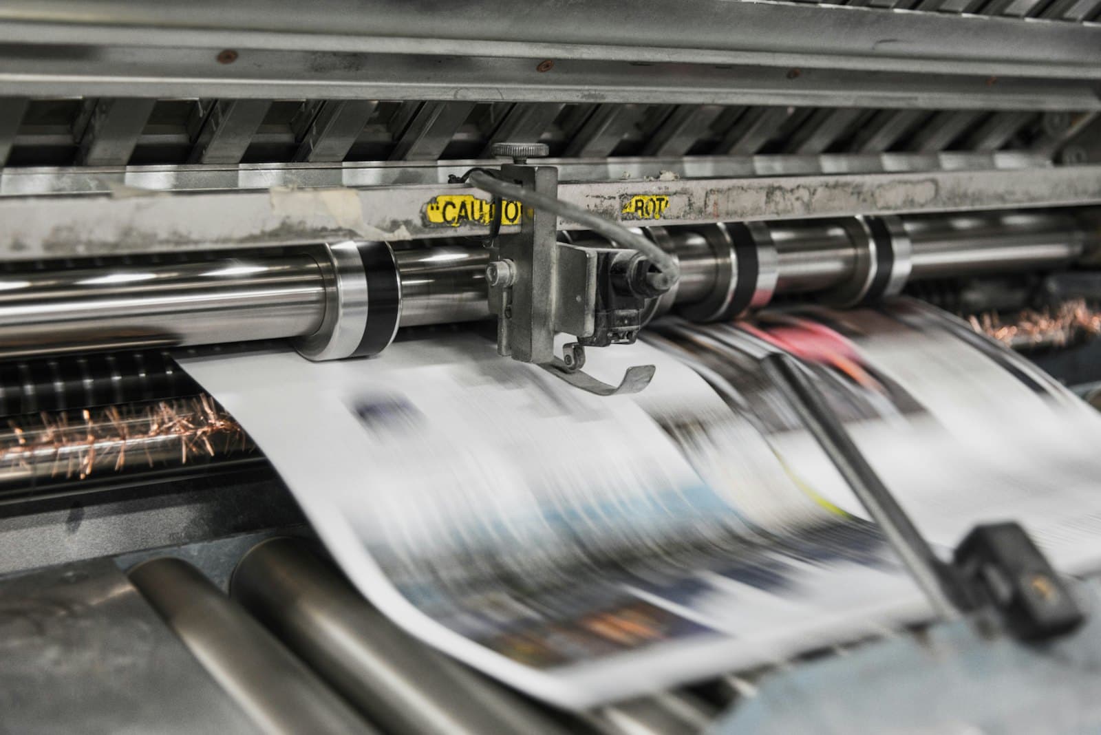 Printed sheets running through the rollers of an offset press.